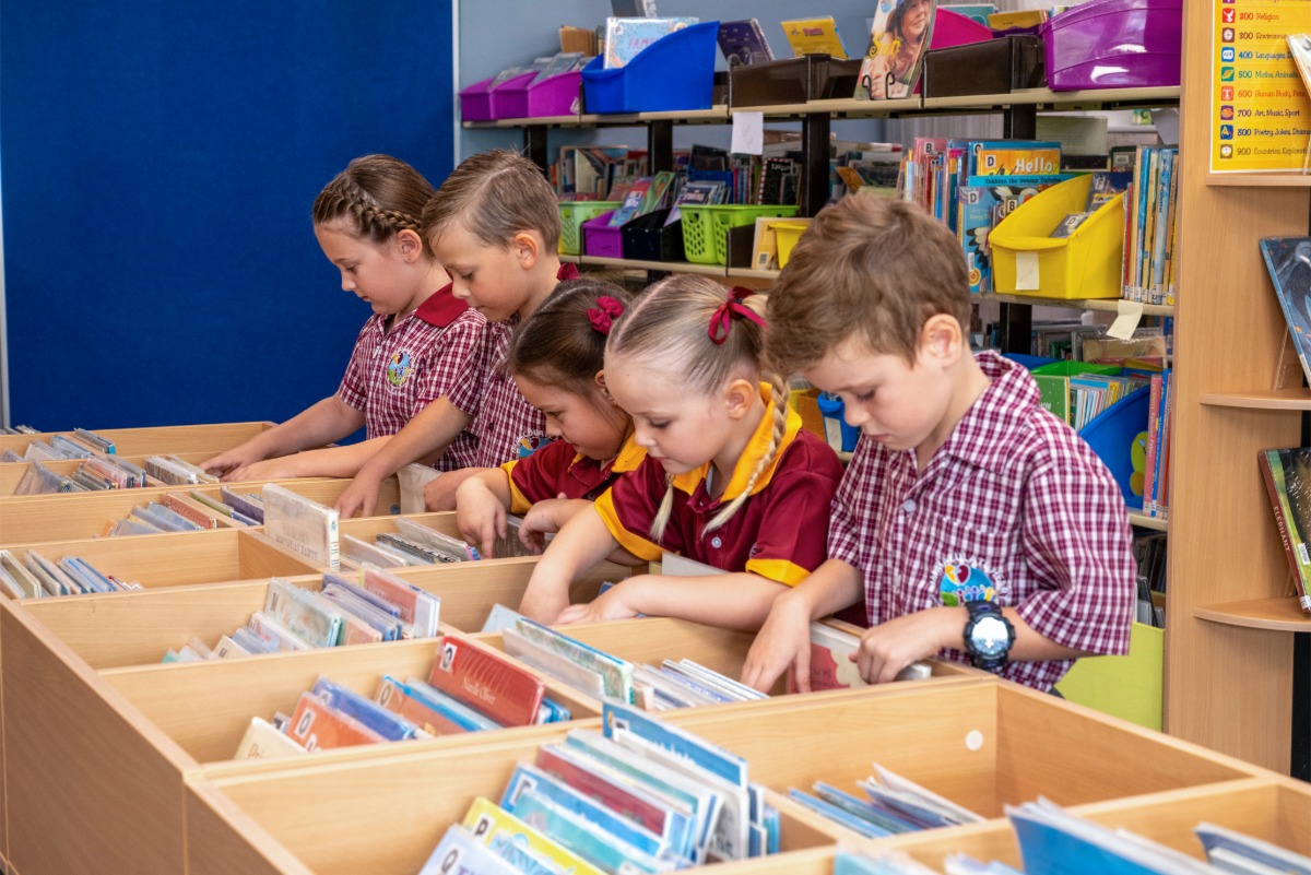 students selecting and exploring books from classroom library shelves during reading activity